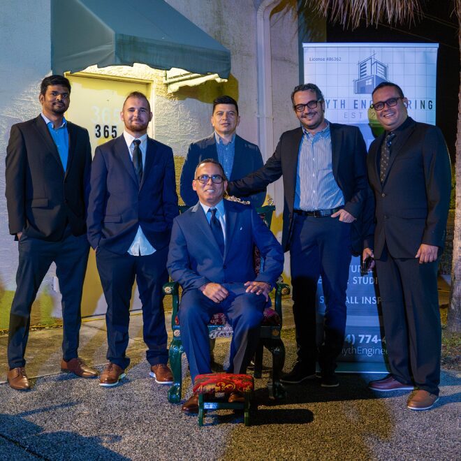 Group of men in suits posing together at an evening event.