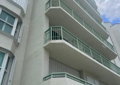 A white building with curved balconies against a cloudy sky.