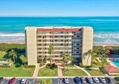 Beachfront high-rise building with parking and a swimming pool alongside the ocean.