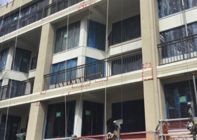 Workers on scaffolding outside a multi-story building under renovation.